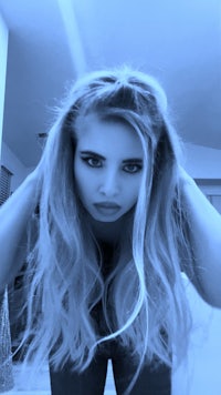 a girl with long blonde hair is posing in a mirror